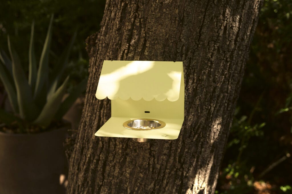 Une mangeoire à oiseaux Picoti jaune suspendue à un arbre.