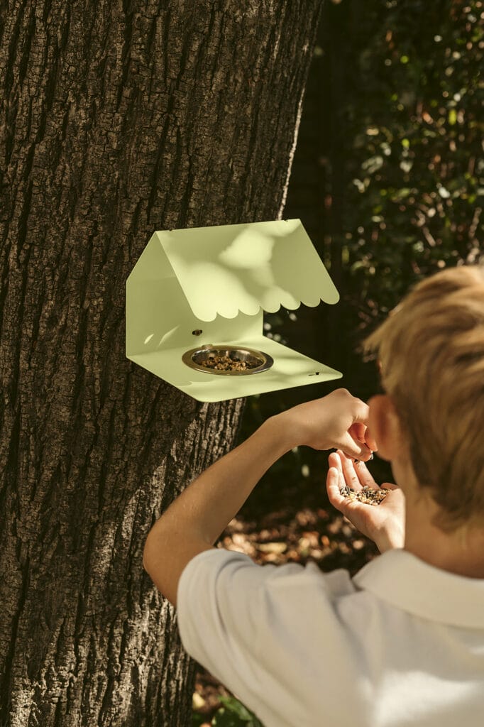 Description modifiée : Un garçon atteint une Picoti mangeoire à oiseaux sur un arbre.