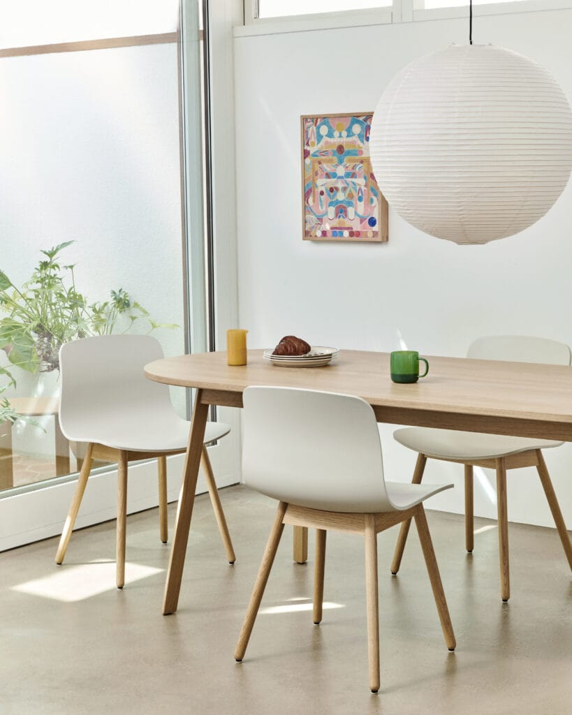 Une table à manger et des chaises Chaise AAC12 dans une pièce avec fenêtres.