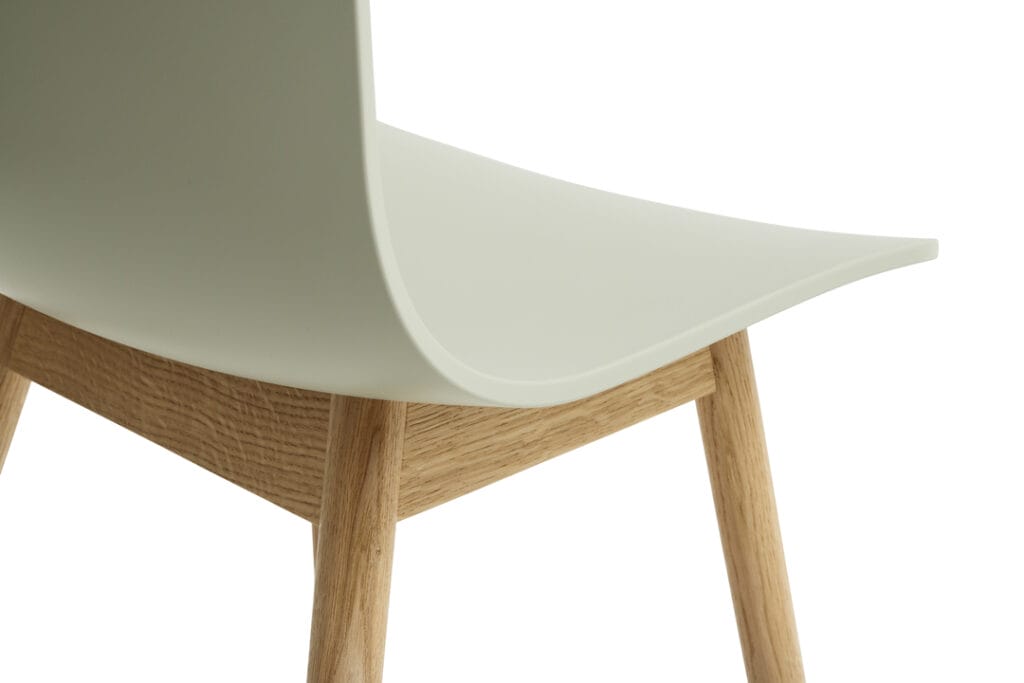 Une chaise blanche AAC12 avec un piètement en bois.