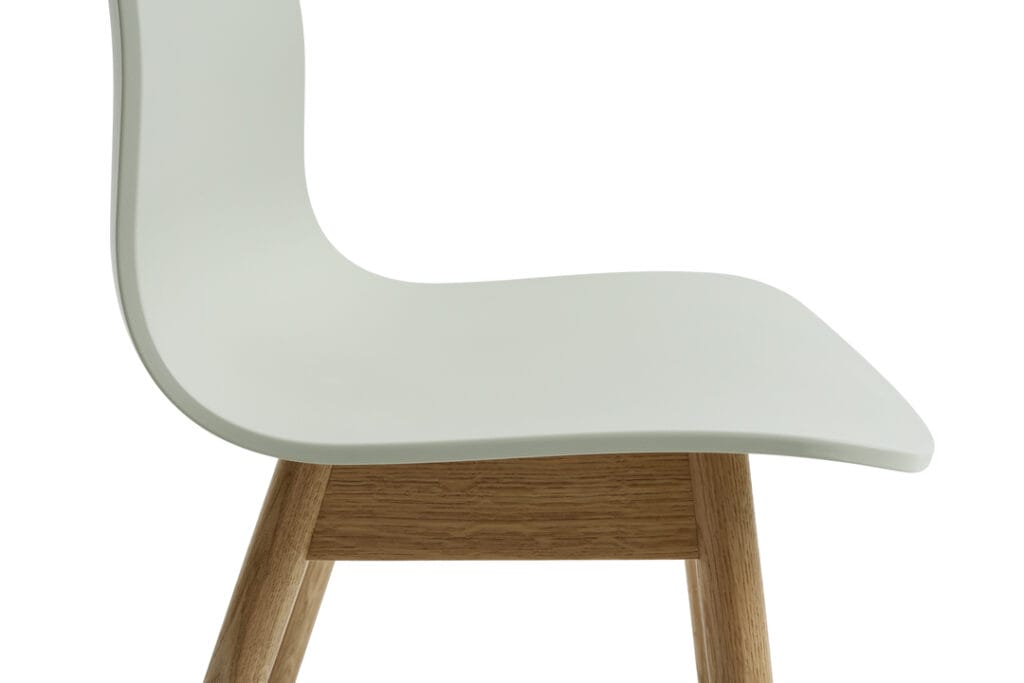 Une chaise en plastique blanc avec des pieds en bois, également connue sous le nom de Chaise AAC12.
