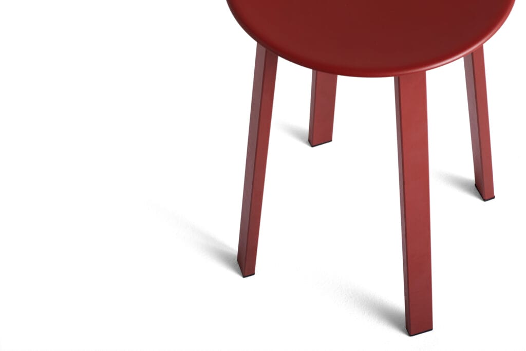 Un tabouret rouge sur fond blanc.