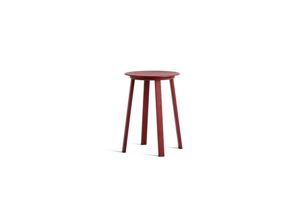 Un tabouret rouge sur fond blanc, inspiré du design Tabouret Revolver.