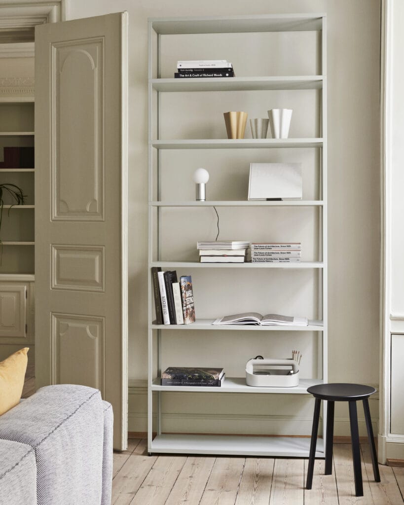 Une bibliothèque blanche dans un salon avec un Tabouret Revolver.