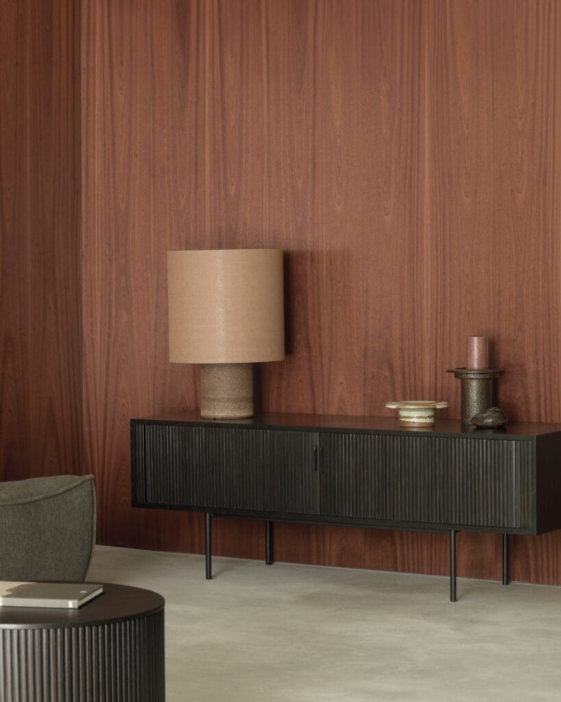 Un séjour avec un mur en bois, une lampe et un meuble TV.