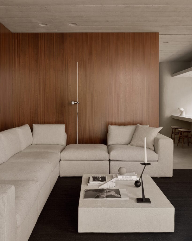 Un salon avec des murs en bois et un canapé blanc, comportant des éléments en bois naturel et une élégante table basse Elements.