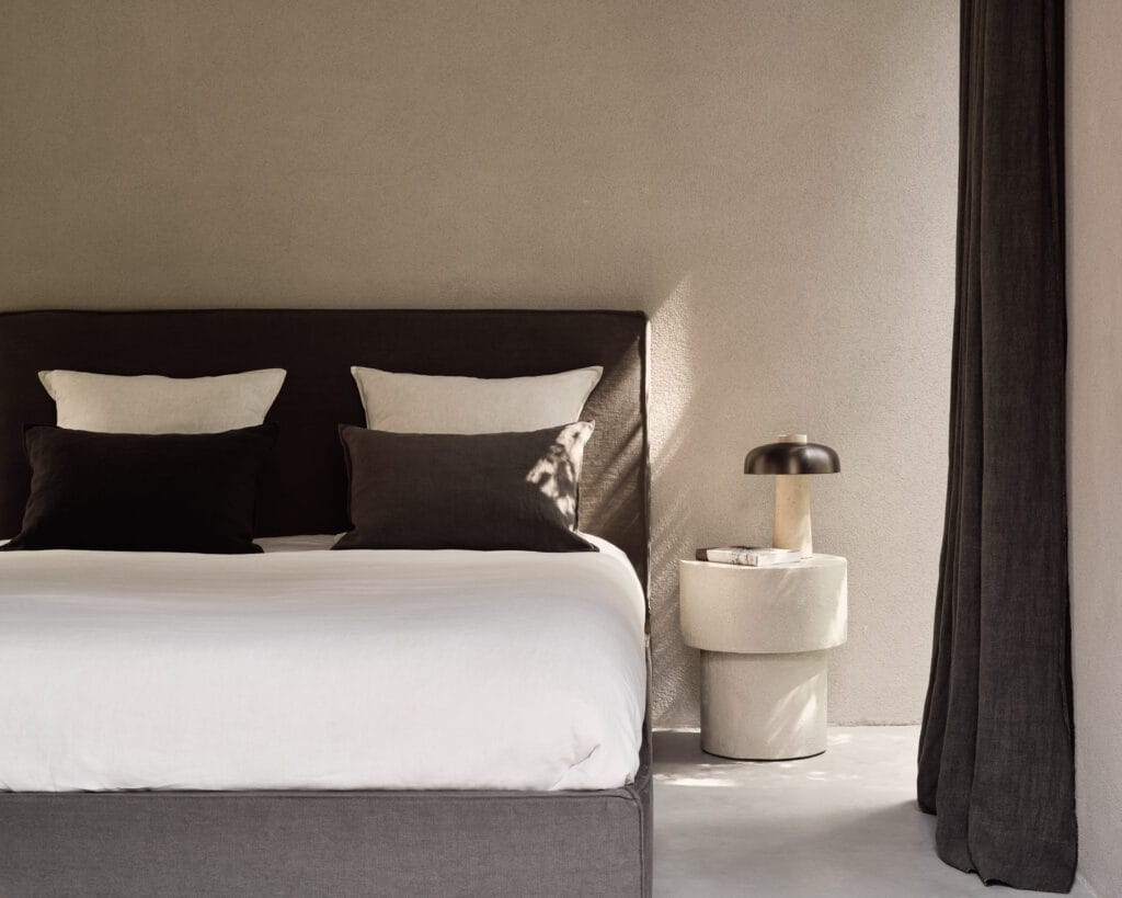 Une chambre avec un lit blanc et des oreillers noirs.