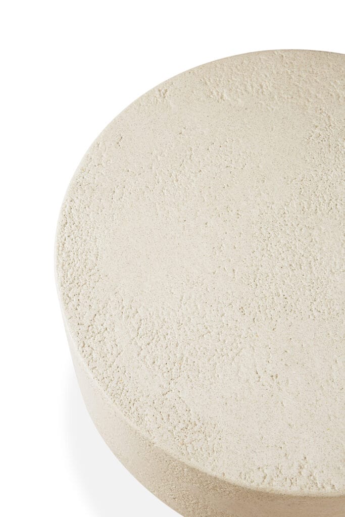 Une table ronde en béton sur une surface blanche avec des éléments en forme de champignon.