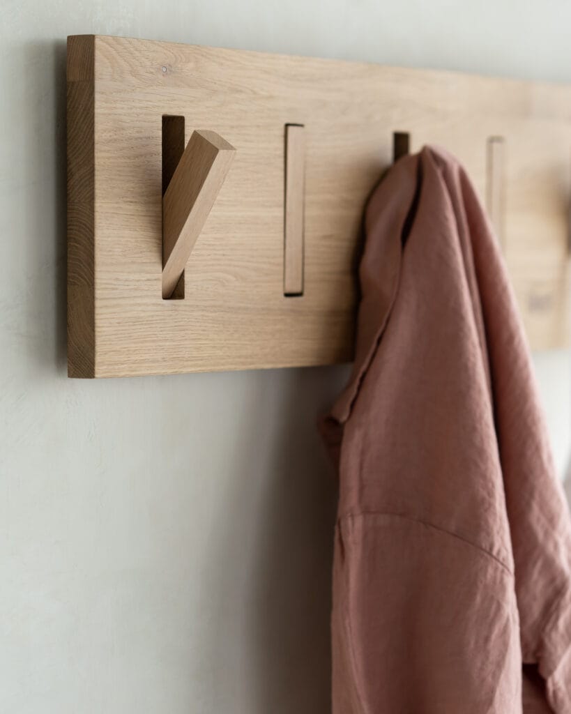 Un porte-manteau en chêne teinté noir avec une chemise rose suspendue.