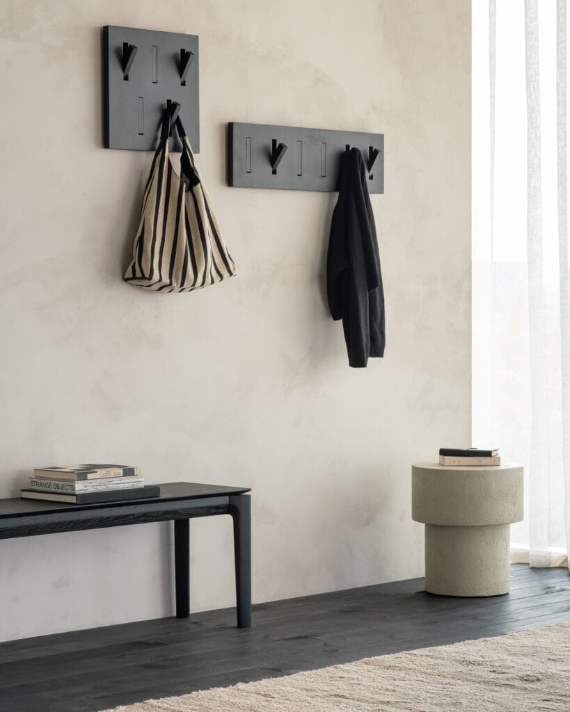 Deux patères porte-manteau en chêne teinté noir accrochées au mur à côté d'un banc.