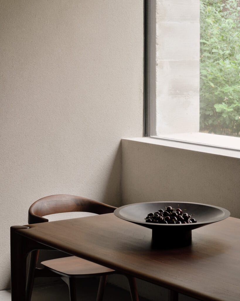 Une table en bois dans une pièce avec une Corbeille Satellite.