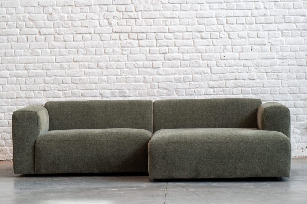 Canapé Annie, tissu Stipa assis sur un canapé vert.