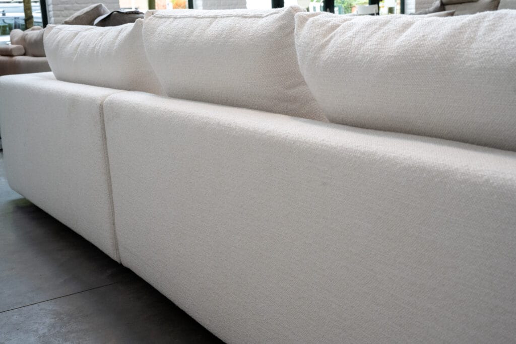 Un canapé Canapé Milou dans un magasin, mettant en valeur l'élégant tissu blanc Heather.