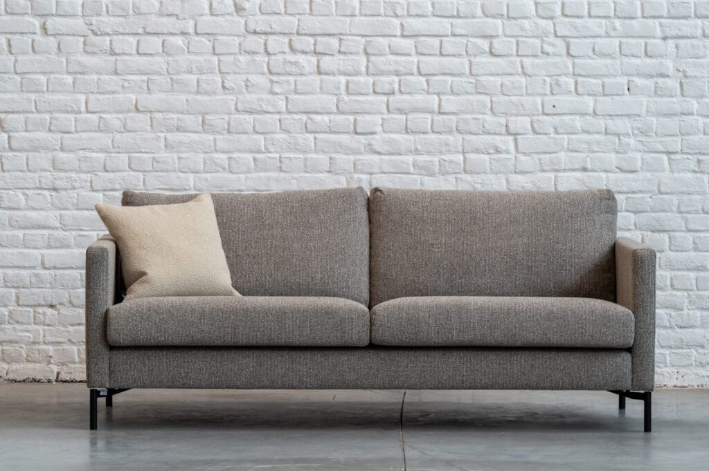 Un Canapé Impulse, tissu Se faufiler devant un mur de briques blanches.