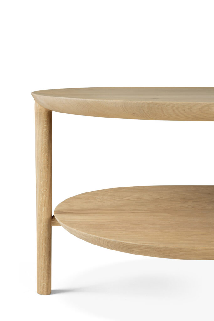 Vue rapprochée d'une table à manger carrée Bok minimaliste avec des bords arrondis et une étagère inférieure. La table présente des lignes épurées et une finition lisse, mettant en valeur le grain naturel du bois.
