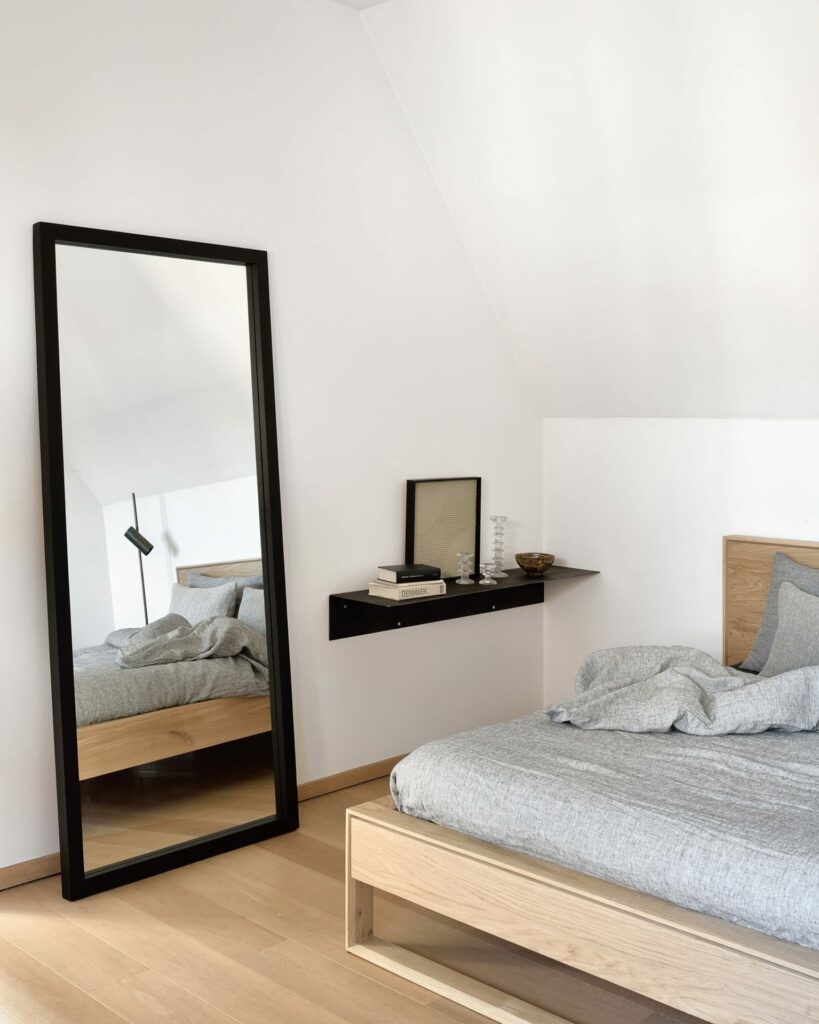 Une chambre avec un lit, un miroir et un cadre lumineux.