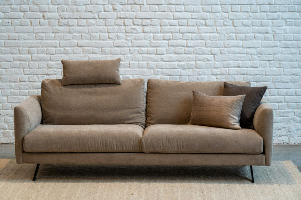 Un canapé beige Expo - Canapé Diva devant un mur de briques blanches.