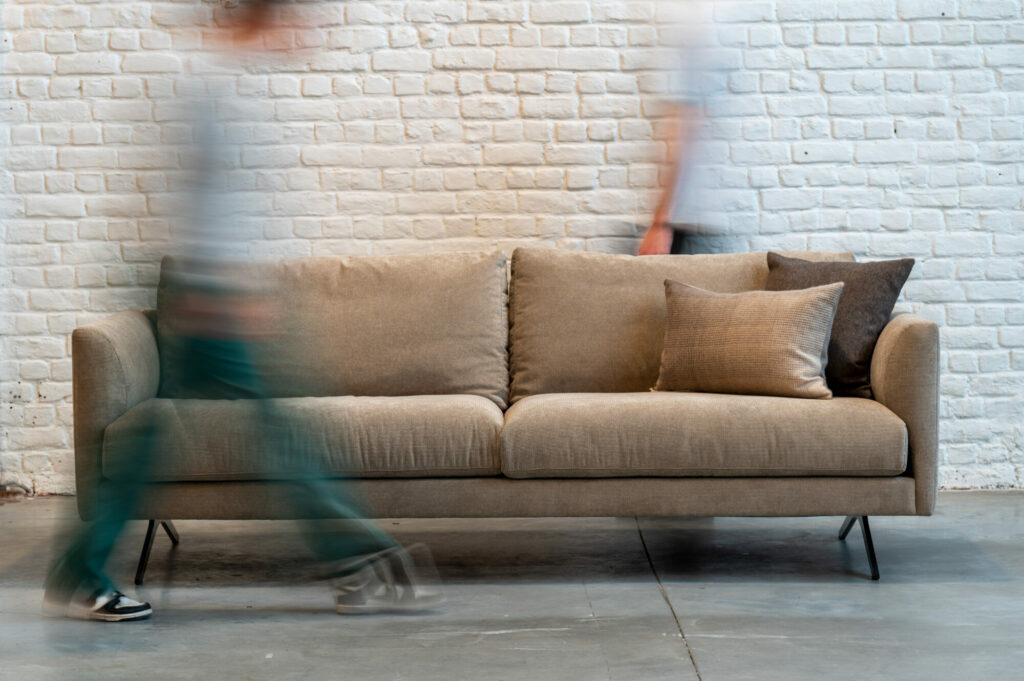 Deux personnes passant devant une Expo - Canapé Diva sur un canapé.