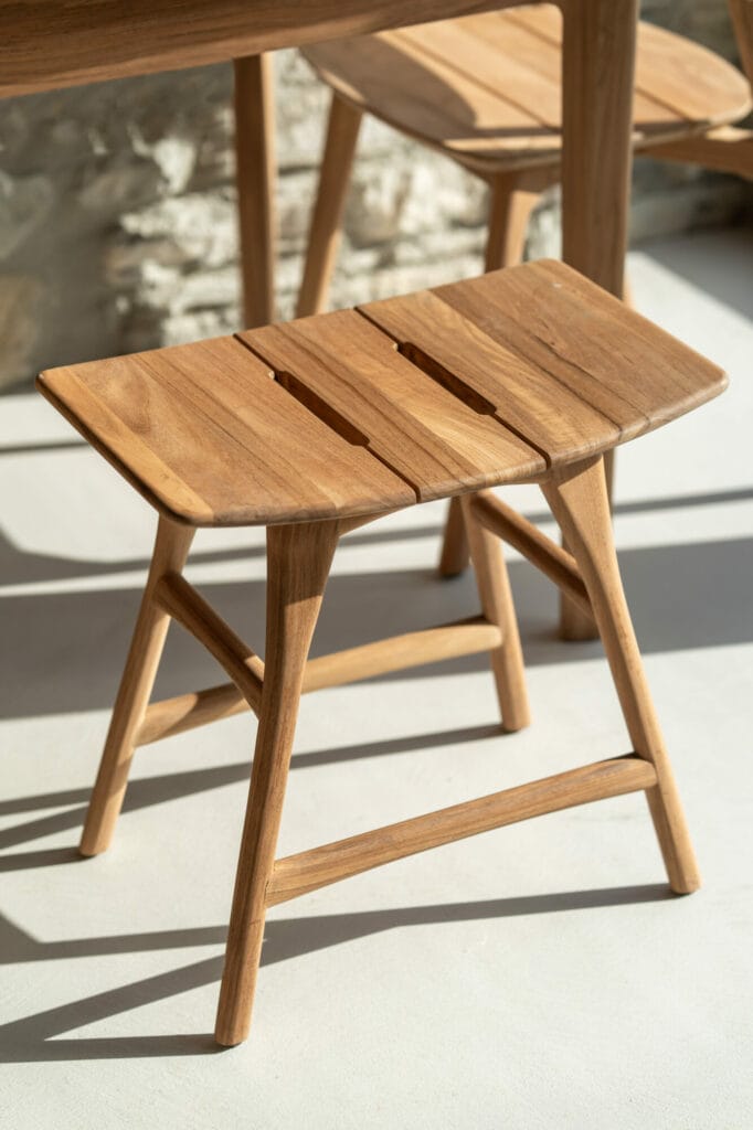 La chaise de salle à manger d'extérieur Jack avec accoudoirs, une chaise de salle à manger d'extérieur, est confortablement perchée sur un banc en bois reposant sur une table en bois.