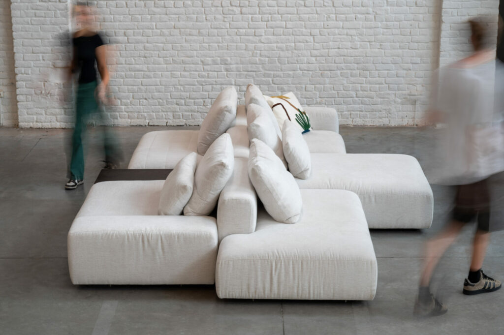 Un groupe de personnes passant devant un canapé blanc, l'Expo - Canapé Reverso, tissu Cottage 3715.