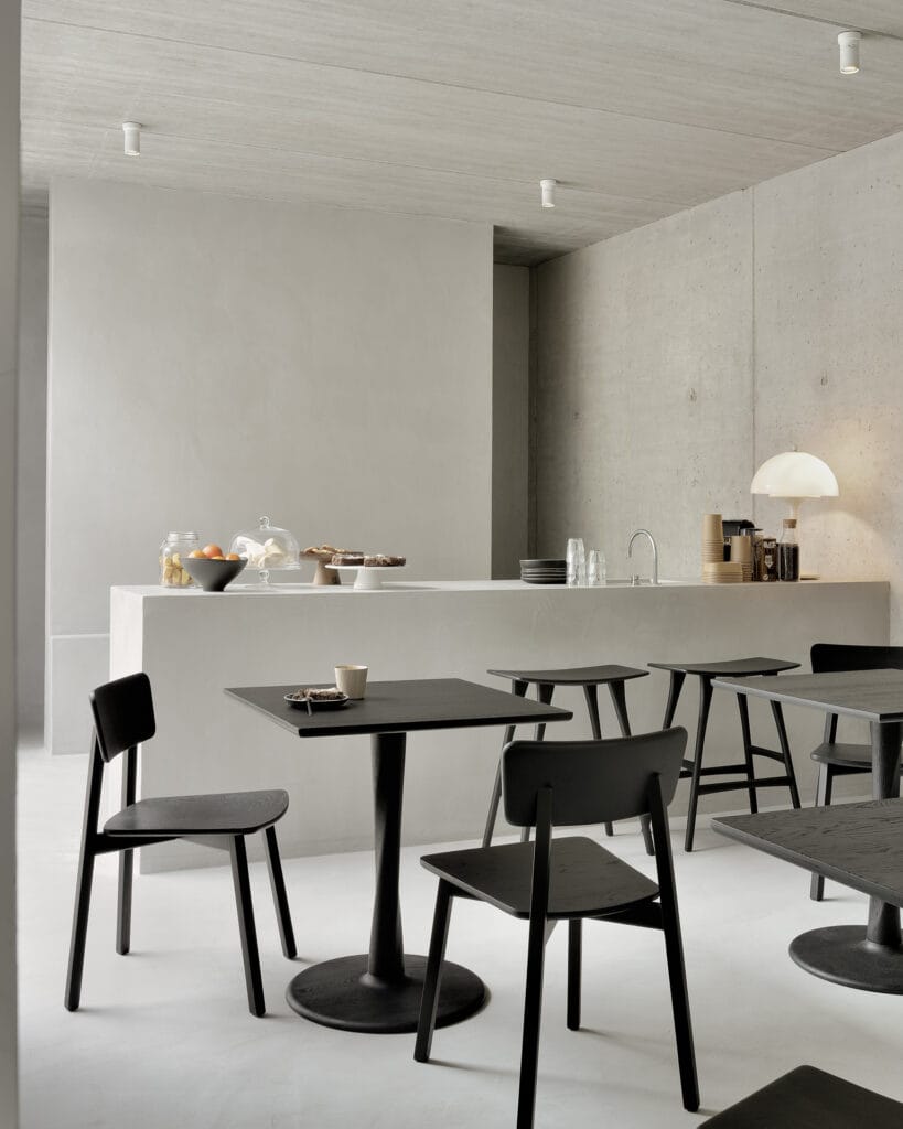Une salle à manger en noir et blanc avec des tables et des chaises en chêne teinté noir vernis.
