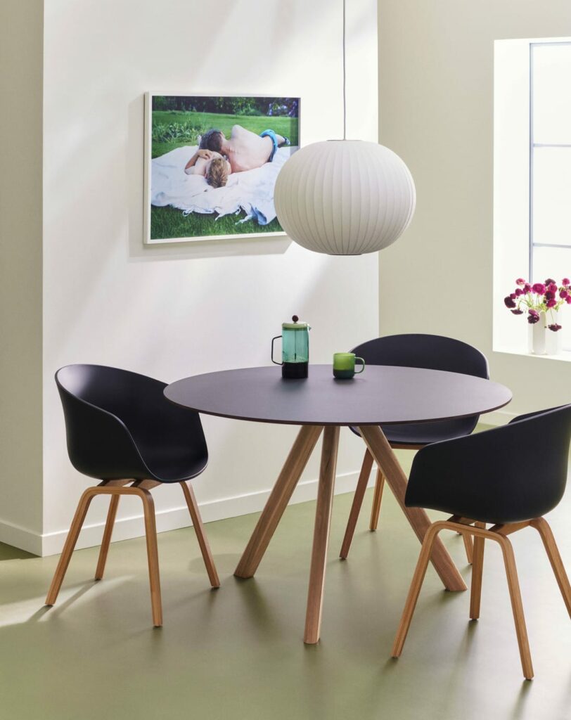 Chaises AAC22 entourant une table à manger dans une pièce avec un tableau au mur.