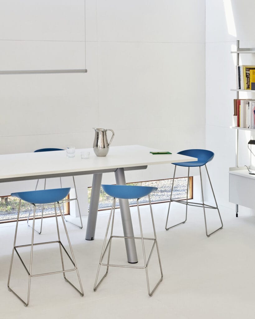 Une table blanche avec des tabourets bleus (Tabouret) dans un bureau moderne.