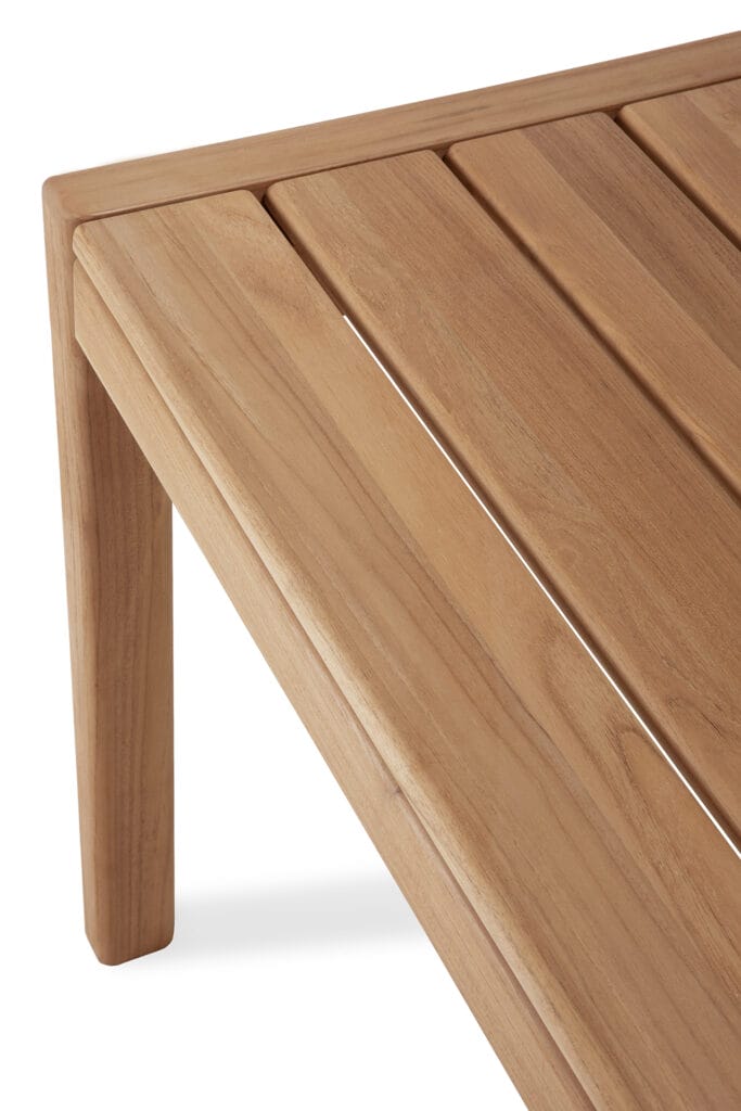 Un gros plan d'une table en bois de teck avec un plateau à lattes.