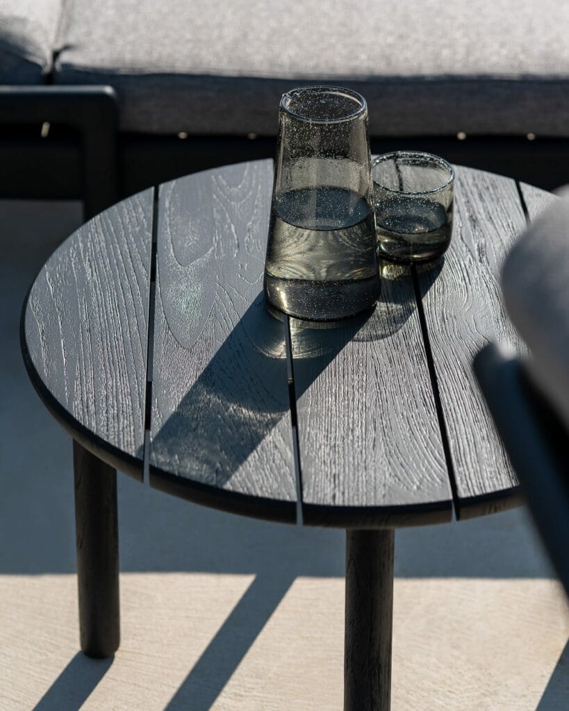 Une Table d'appoint avec un verre de boisson dans un jardin.