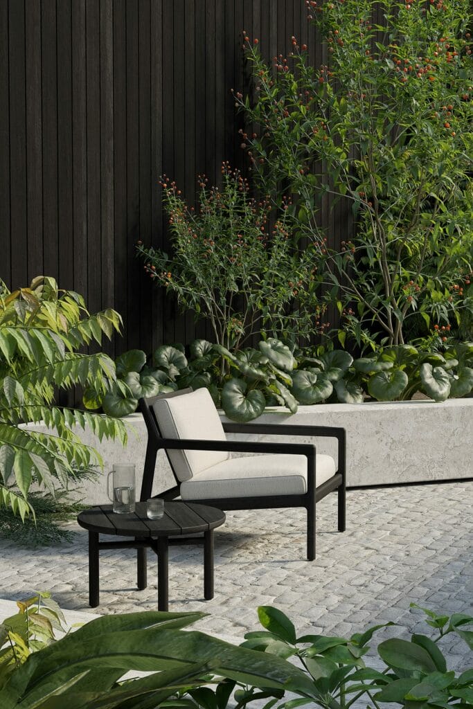 Une table d'appoint de jardin en teck teinté noir dans un jardin.