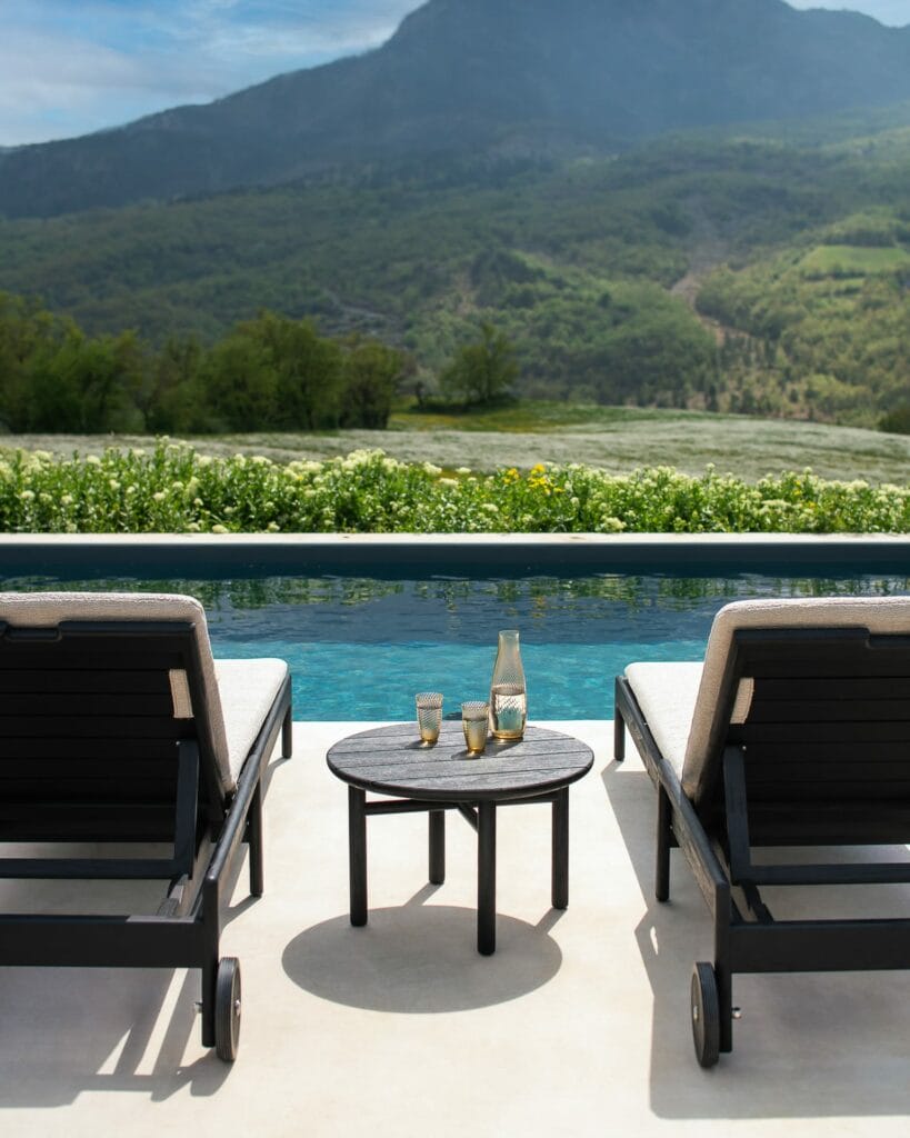Une table d'appoint de jardin Quatro avec des chaises en teck noir.