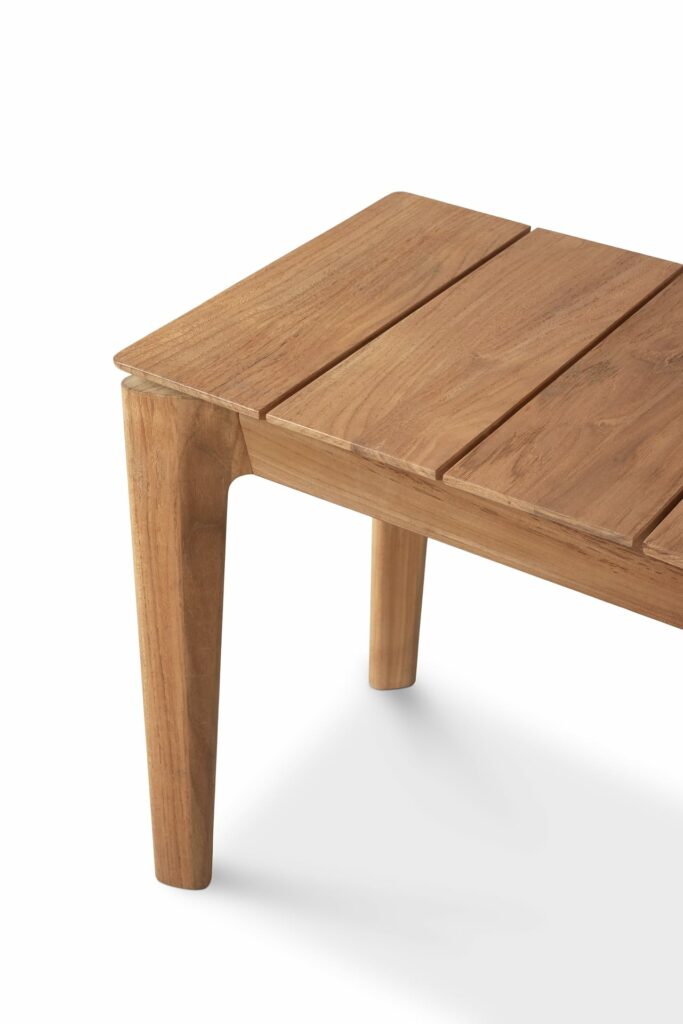Une table basse en teck sur fond blanc.