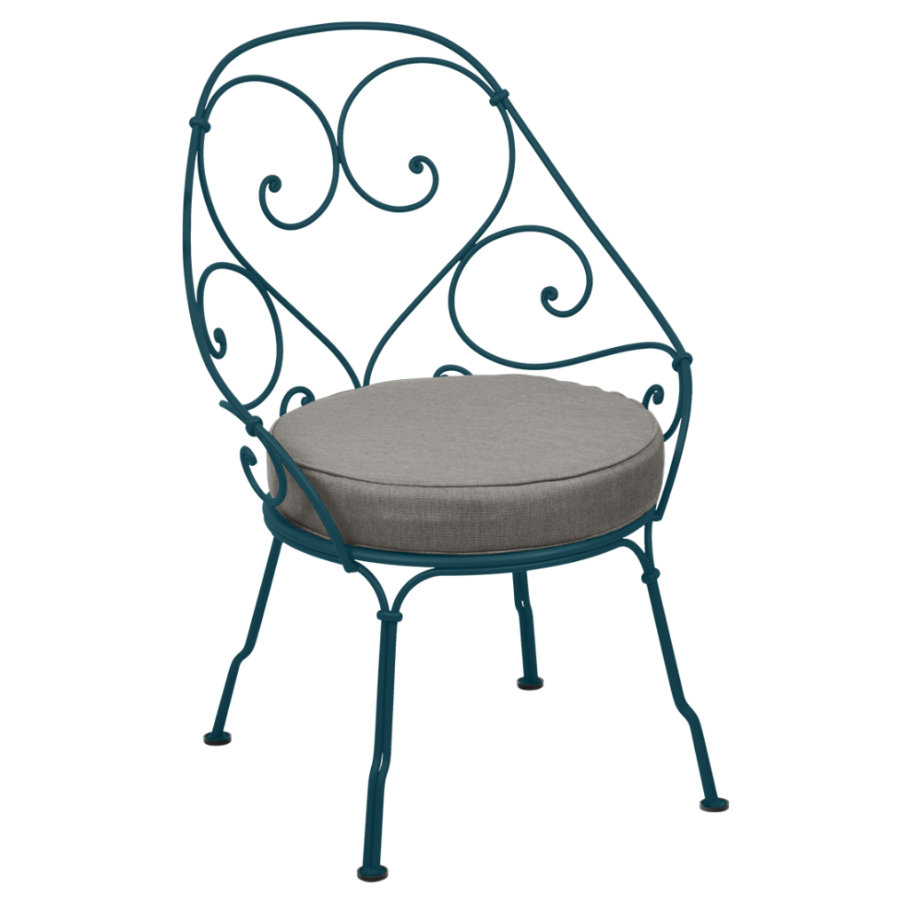 Une chaise en fer forgé bleu sarcelle avec un coussin datant de 1900.