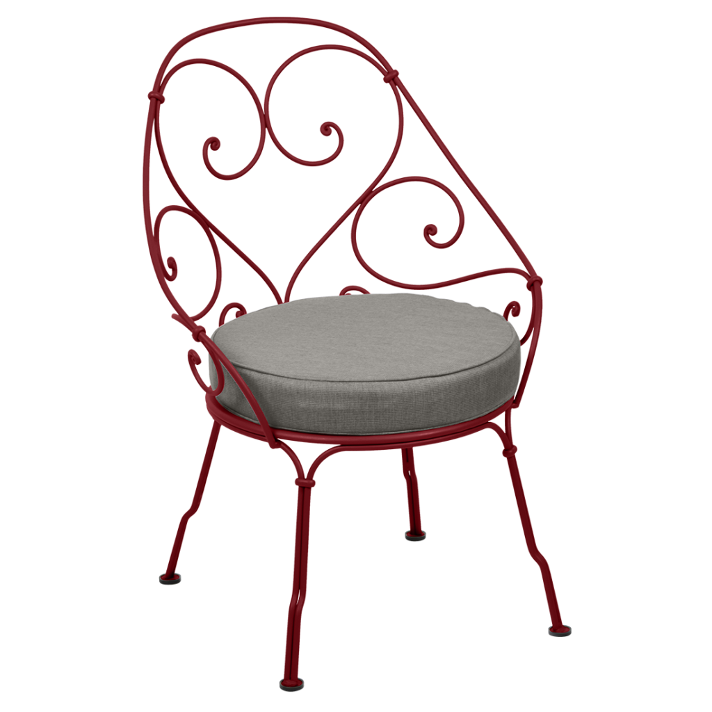 Une chaise en fer forgé rouge avec un coussin gris datant de 1900.