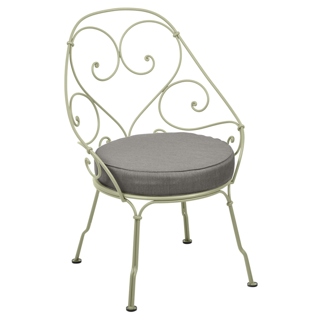 Un fauteuil des années 1900 avec un coussin gris.