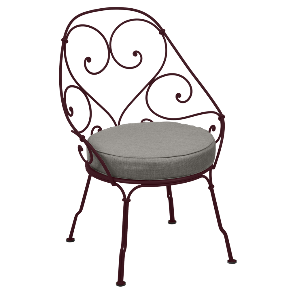 Une chaise en fer forgé des années 1900 avec un coussin.