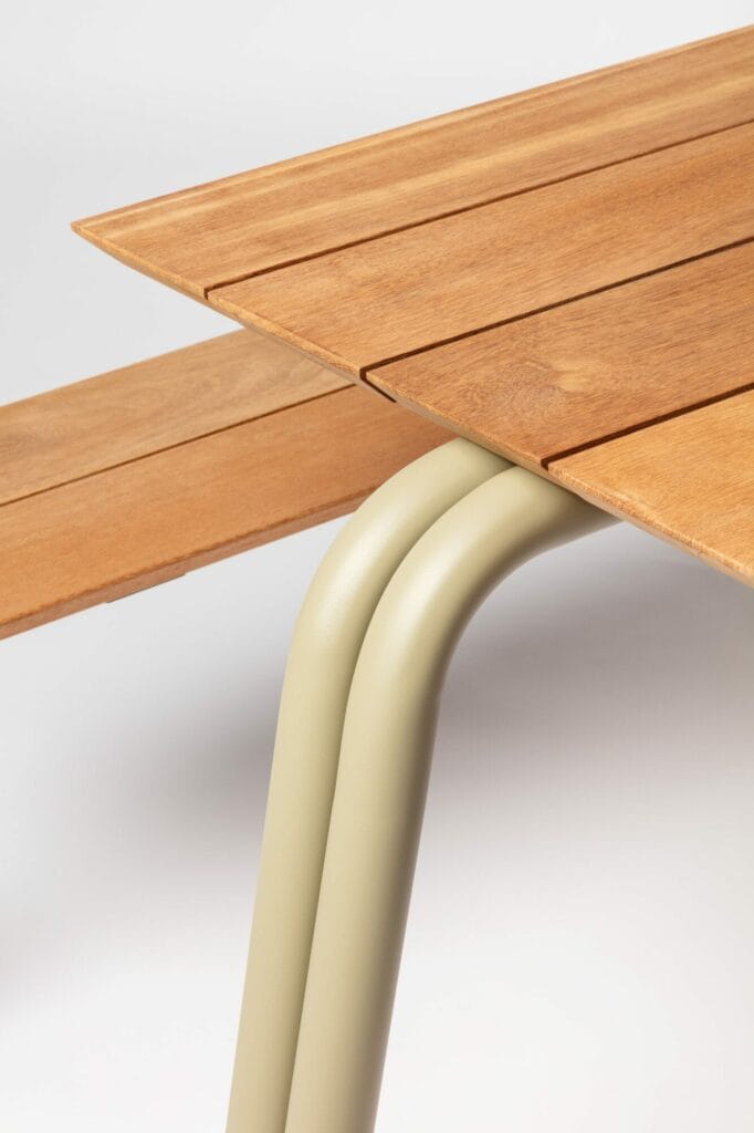 Vue rapprochée d'un petit coin de table montrant un plateau en bois et un pied incurvé de couleur gris clair.