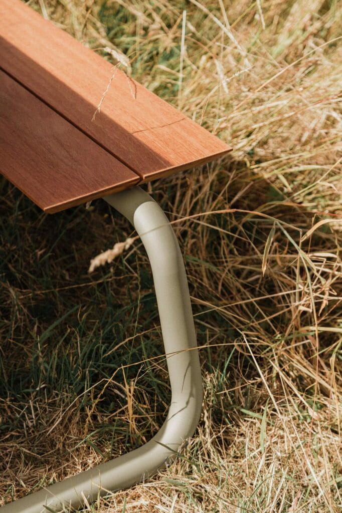 Un gros plan d'une table gris clair avec des pieds en métal posés sur une surface herbeuse.