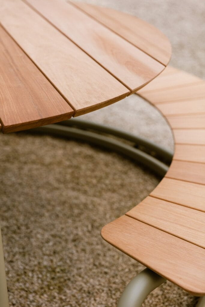 Gros plan de The Circle - ensemble table + bancs - Gris clair (RAL7044) avec bords lisses et incurvés sur moquette.