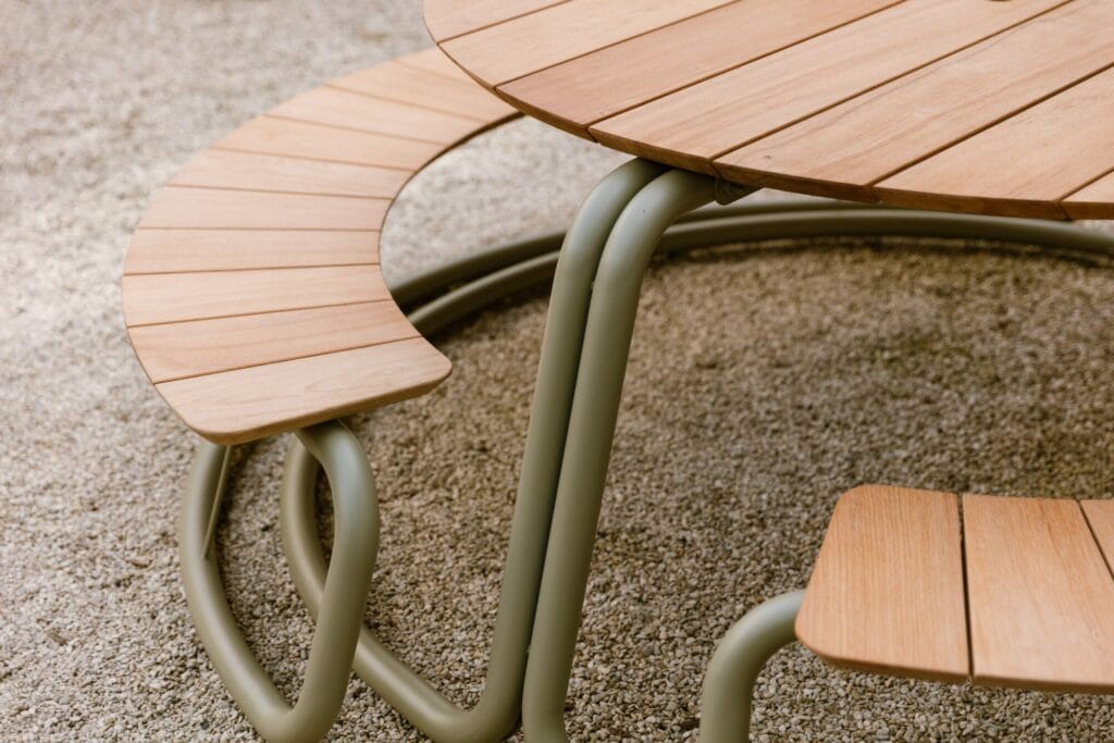 The Circle - ensemble table + bancs - Gris clair (RAL7044) avec pieds en métal courbés et chaise assortie sur un tapis texturé gris clair.