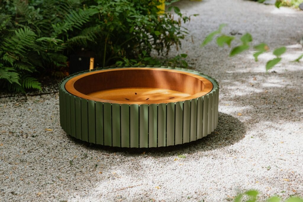 Un banc circulaire en acier Corten, The Ring, entouré de graviers et de verdure.