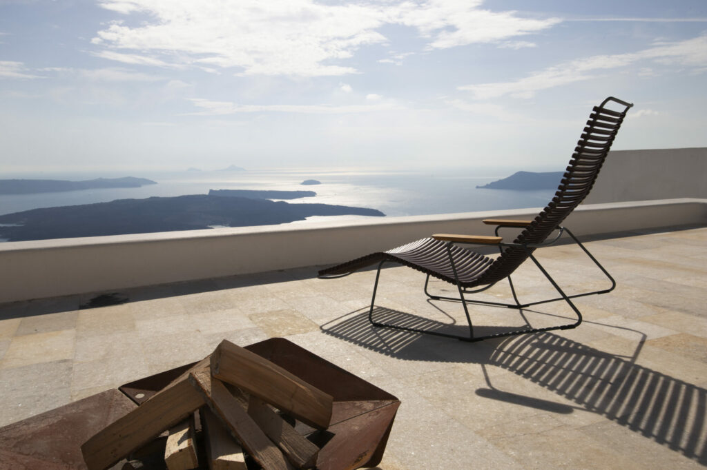 Un Click Sunrocker sur une terrasse surplombant un paysage marin pittoresque avec des îles au loin.