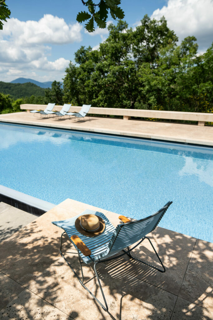 Une piscine extérieure avec un Sunrocker et un chapeau par une journée ensoleillée, surplombant une vue panoramique sur les montagnes.