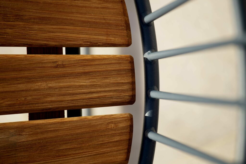 Gros plan d'une chaise à bascule Paon en bois et métal détaillant la jonction des lattes de bois et du cadre métallique.