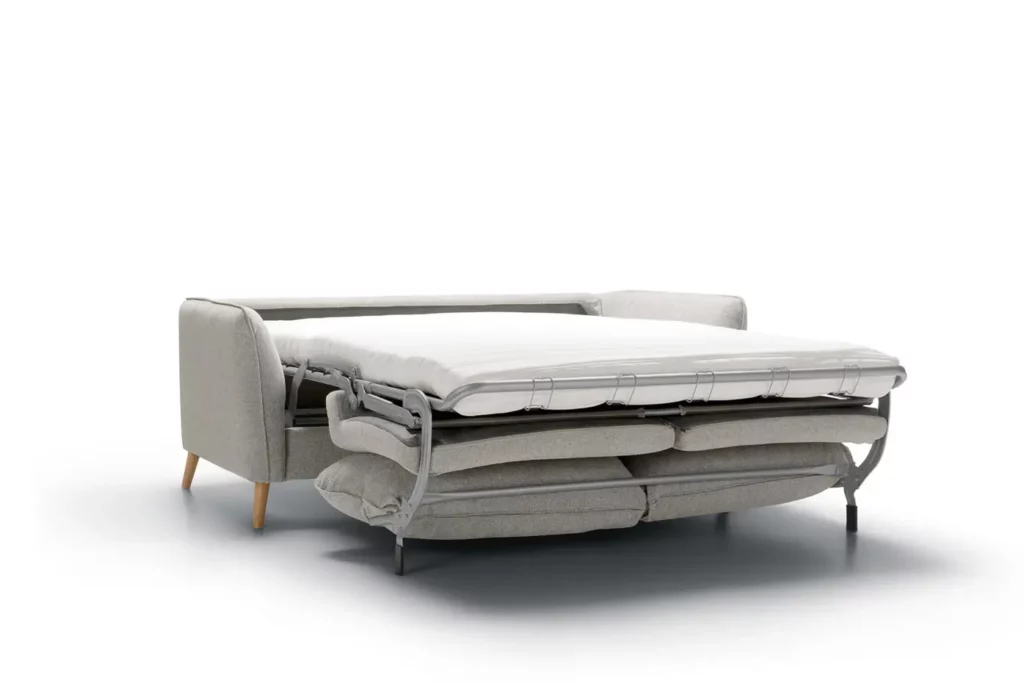 Phrase avec le nom du produit : Canapé-lit gris Canapé Lucy partiellement déplié avec un matelas blanc, sur un fond blanc uni.