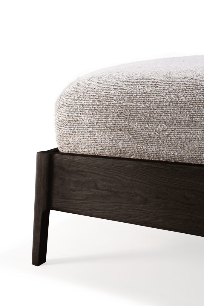 Gros plan du lit Air présentant un cadre en chêne verni marron avec un matelas rembourré de couleur claire, sur un fond blanc immaculé.