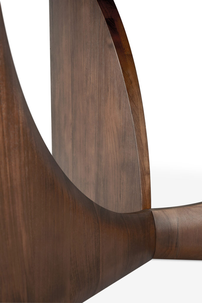 Vue rapprochée de la table à manger géométrique - teck verni - marron - ronde avec un design incurvé et une finition lisse et sombre.