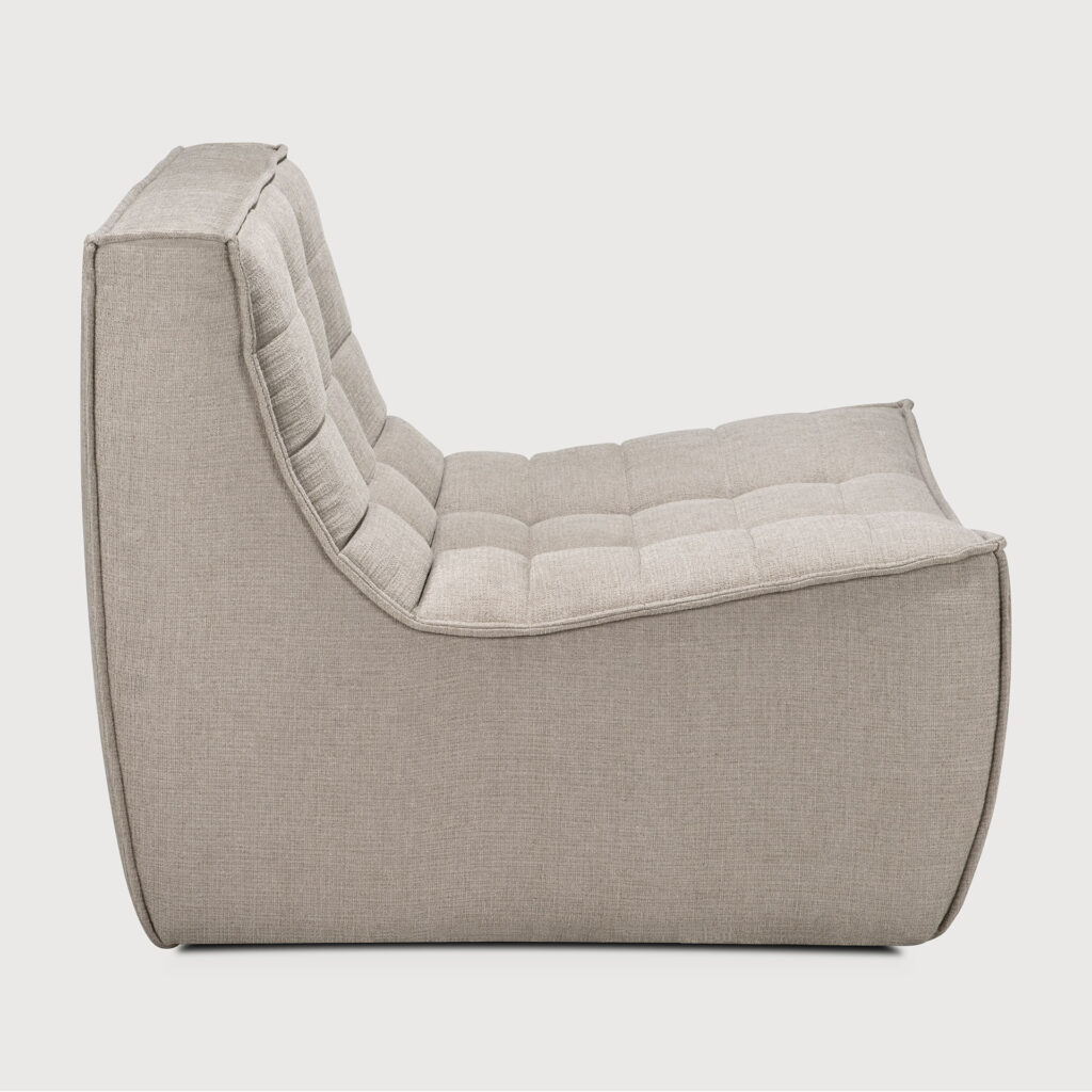 Vue latérale d'une chaise longue rembourrée moderne de couleur taupe avec un design matelassé et une silhouette incurvée, rappelant l'élégance intemporelle d'un canapé N701 de couleur écru.