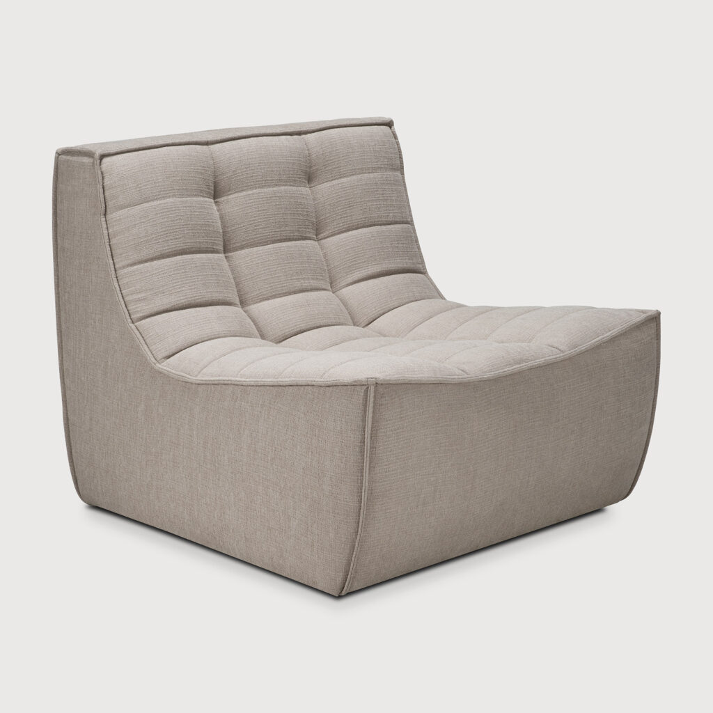 Une chaise longue beige moderne sans accoudoirs avec un siège et un dossier matelassés et rembourrés. La chaise N701 a un tissu écologique écru et un profil bas avec un angle légèrement incliné.
