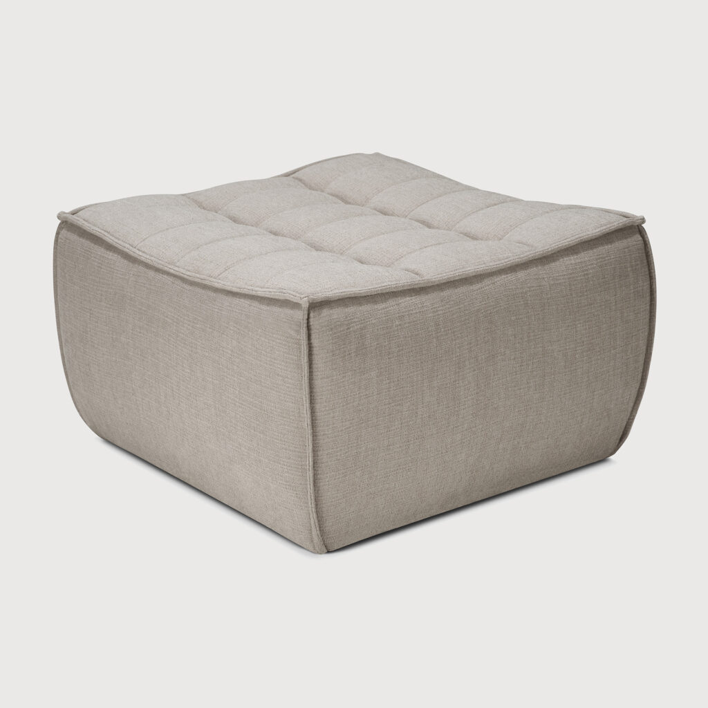 Un pouf carré en tissu écologique écru avec un dessus doux et touffeté et des côtés lisses. Parfait comme repose-pieds pour la détente.